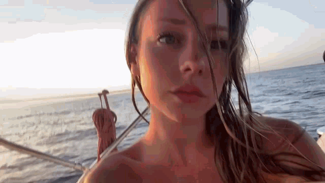a woman is sitting on a boat in the ocean and taking a selfie .
