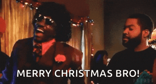 a man in a suit and tie is standing next to a man in a black shirt and saying merry christmas bro .