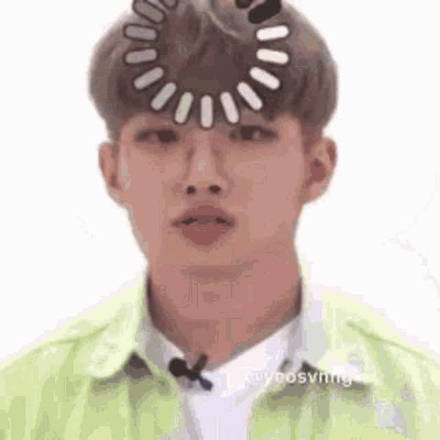 a man with a circle on his head is wearing a green shirt .