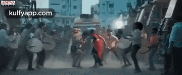 a group of people are dancing in front of a truck on a street .