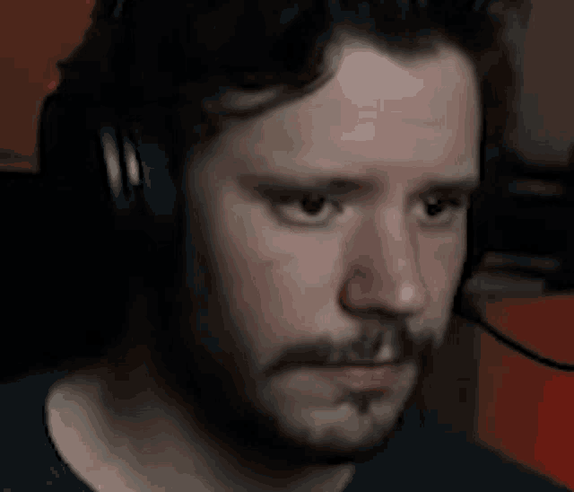 a man with a beard wearing headphones is making a face .