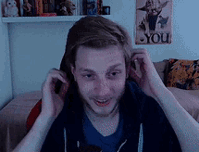 a man adjusts his ear buds in front of a poster that says you