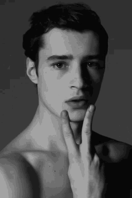 a shirtless man is making a peace sign with his hand