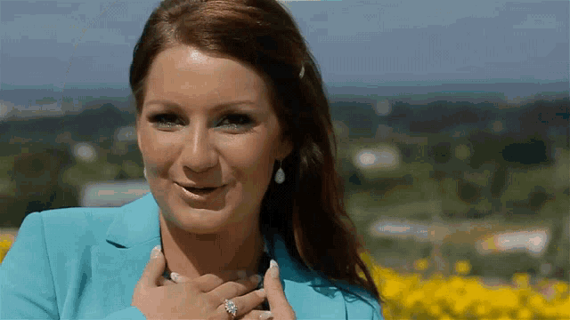 a woman wearing a blue jacket and earrings is smiling