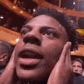 a close up of a man 's face with his hands on his face in a crowd .