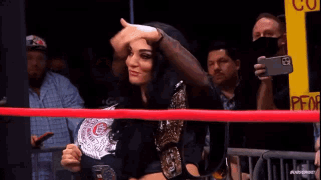 a woman in a wrestling ring holding a belt that says ' g ' on it