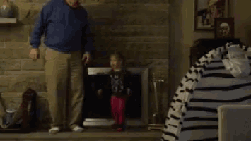 a man stands next to a little girl in front of a fireplace