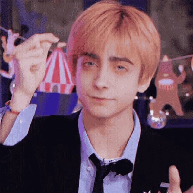 a young man in a suit and tie is holding a string of lights