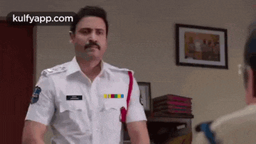 a man in a police uniform is talking to another man .