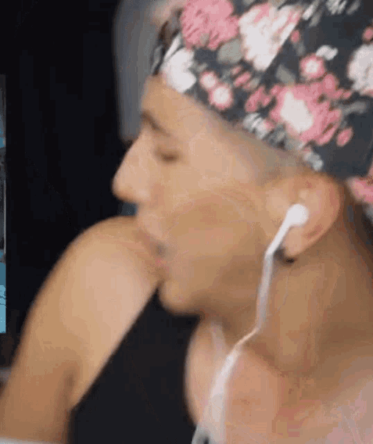 a man wearing a floral headband and ear buds is yawning .