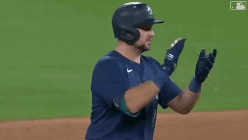 a baseball player wearing a helmet and gloves is clapping his hands on the field .