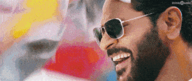 a close up of a man with a beard wearing sunglasses and smiling .