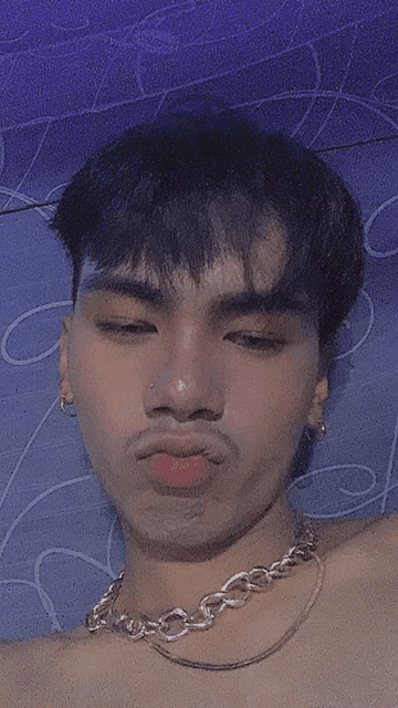 a young man with a necklace around his neck is making a funny face