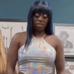 a woman with blue hair is wearing a holographic top and glasses .
