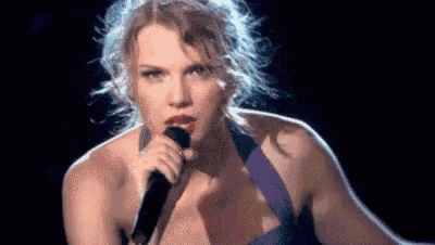 taylor swift is singing into a microphone on a stage .