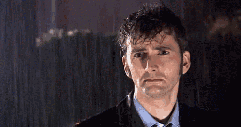a man in a suit and tie is crying in the rain at night .