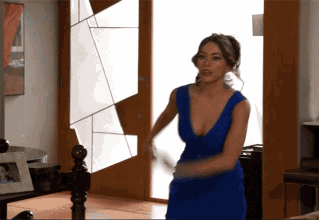 a woman in a blue dress is standing in front of a glass door