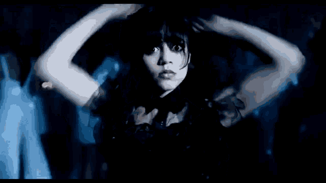 a woman in a black dress is dancing in the dark .