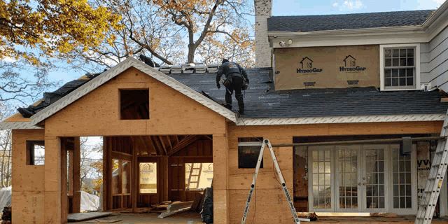 a man is working on the roof of a house which is being remodeled
