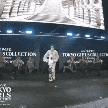 a group of people are dancing on a stage with a sign that says tokyo girls collection on it