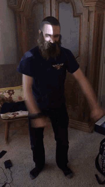 a man with a beard is standing next to a chair with a floral pillow