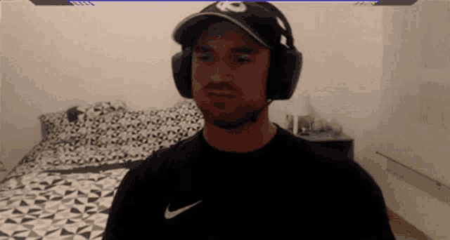 a man wearing headphones and a kc hat looks at the camera