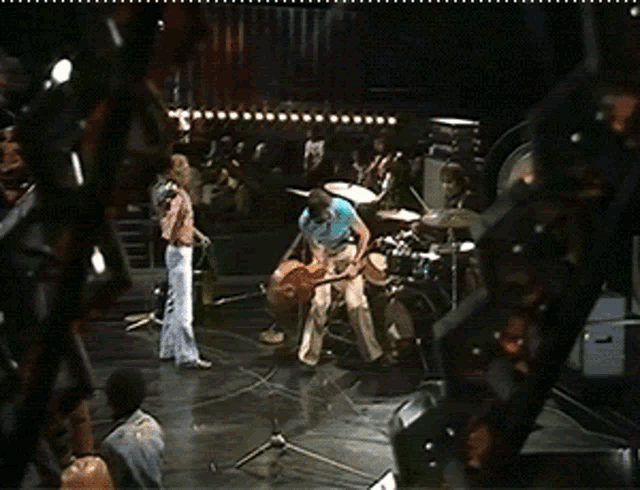 a man in a blue shirt is playing a drum set on a stage