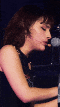 a woman singing into a microphone while playing a keyboard