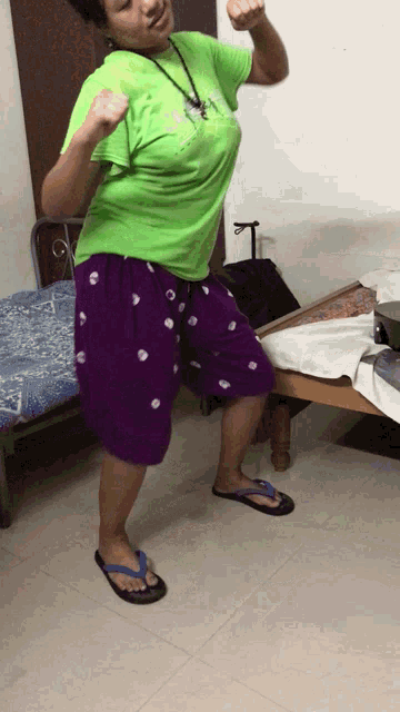 a woman in a green shirt and purple shorts is standing on a tiled floor