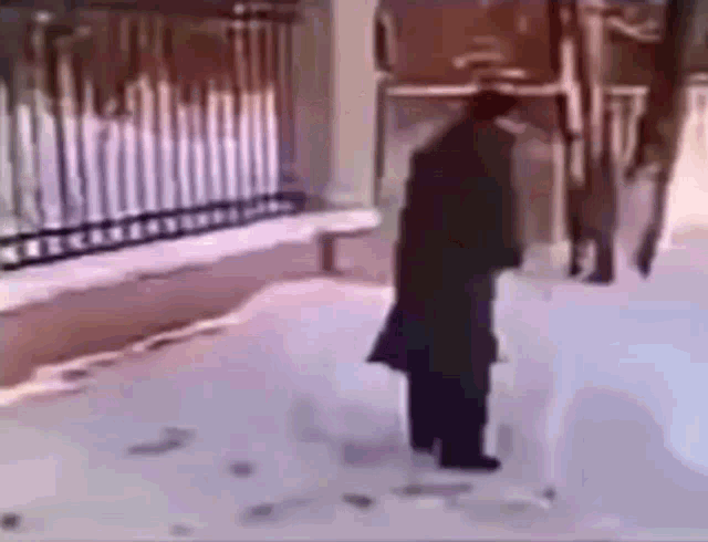 a man is standing in the snow with a cane in front of a building .