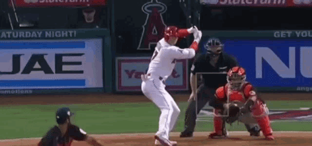 a baseball player is swinging a bat at a pitch while a catcher watches .