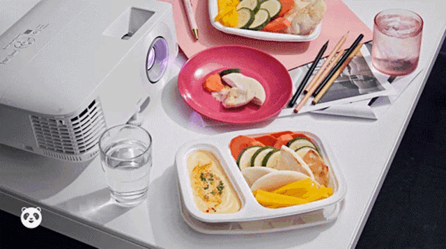 a projector is sitting on a desk next to a plate of food