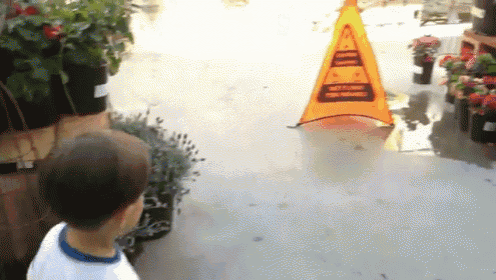 a boy standing in front of a caution sign