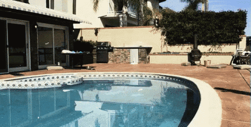 a large swimming pool in front of a house with a sliding glass door