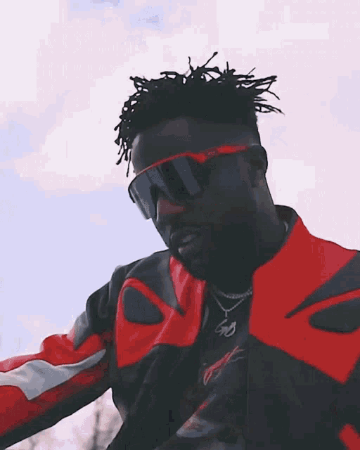 a man wearing sunglasses and a red and black jacket with the letter p on the front