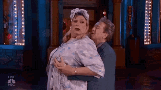 a man is holding a woman in his arms while she is dancing on a stage .