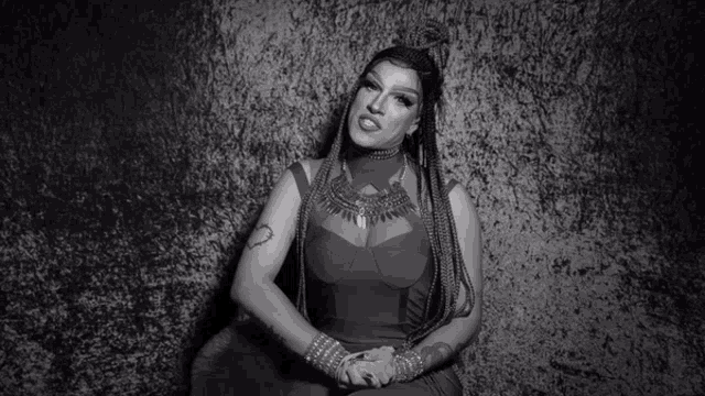 a black and white photo of a woman with braids and a tattoo on her arm