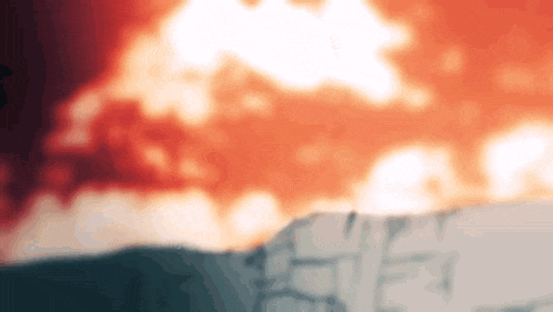 a blurred image of a large explosion with a mountain in the foreground