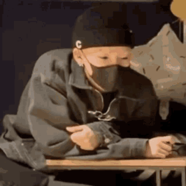 a man wearing a mask is sitting at a table .