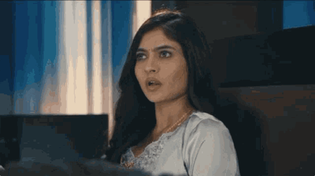a woman is sitting on a bed with her mouth open and looking at the camera .