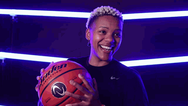 a woman is smiling while holding a basketball that says evolution on it