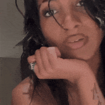 a close up of a woman 's face with a ring on her finger .
