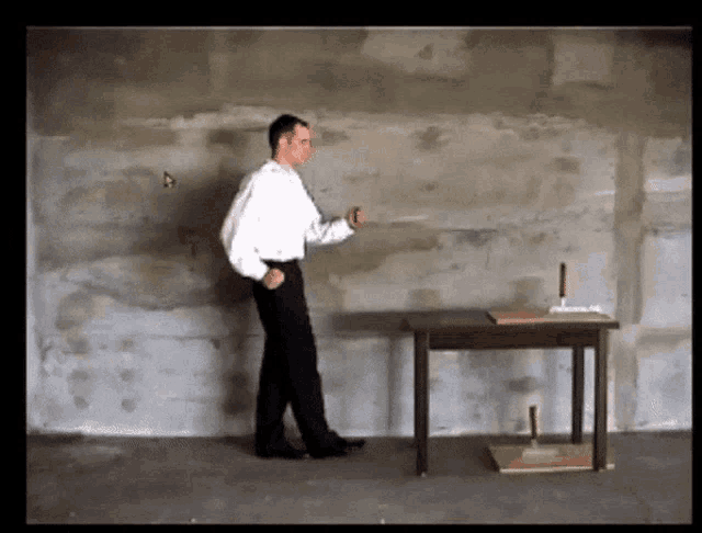 a man in a white shirt is standing in front of a concrete wall