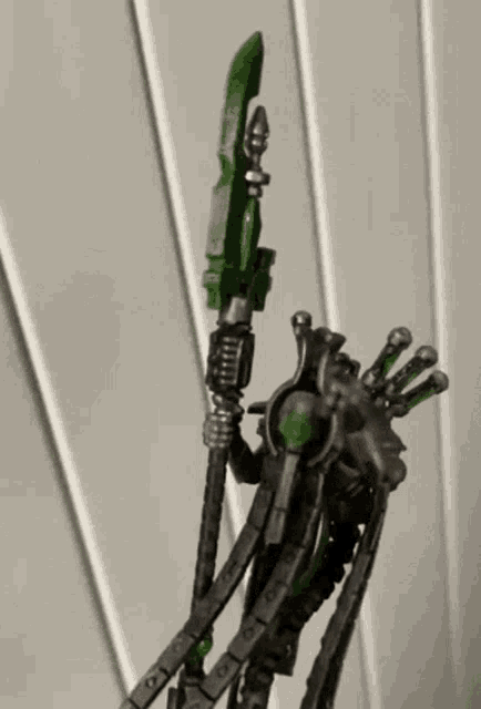 a toy robot with a green sword is holding a green sword in its hand .