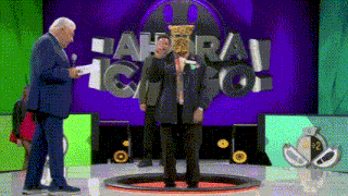 a man in a suit stands on a stage in front of a sign that says " ahora "