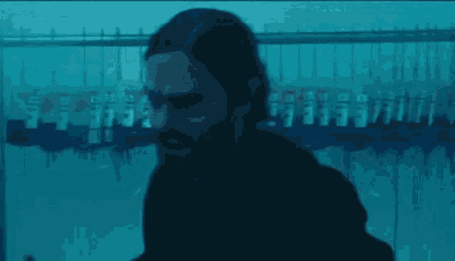 a man with long hair and a beard is standing in front of a row of clothes racks .