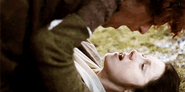 a man is kissing a woman on the forehead while she is laying on the ground .