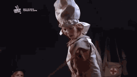 a woman in a nurse costume is standing in a dark room with blood coming out of her chest .