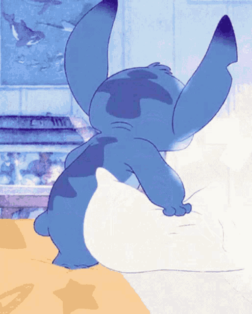 a blue cartoon character is sitting on a bed