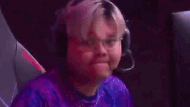 a man in a purple shirt is sitting in front of a monitor